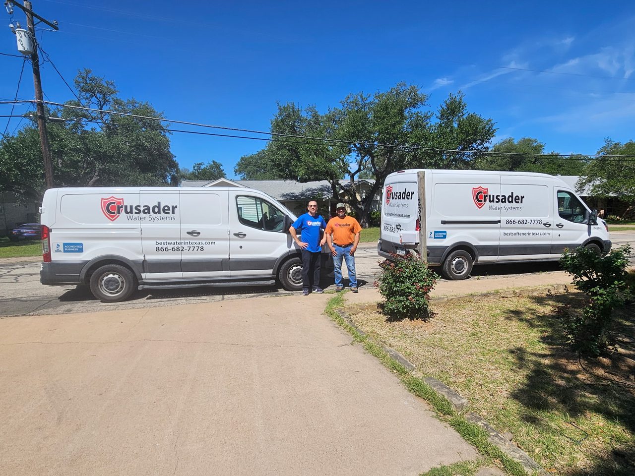 Crusader of Texas team standing between two branded Crusader Water Systems service vans